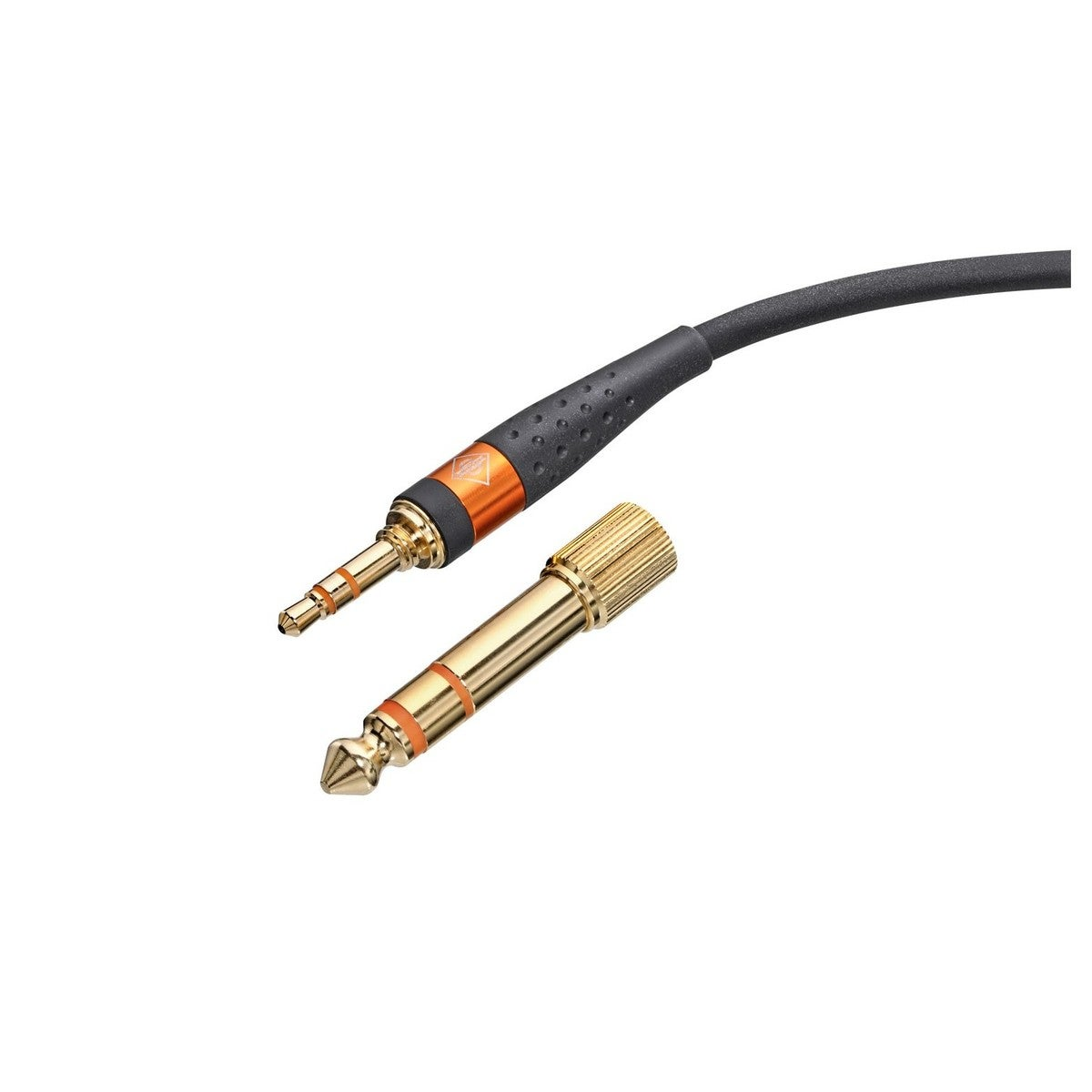 Złoty adapter 6,3 mm leży obok wtyczki 3,5 mm z czarnym kablem.