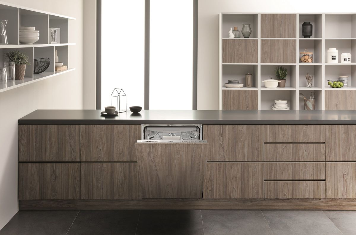 Cucina moderna con lavastoviglie aperta, mobili in legno e mensole.