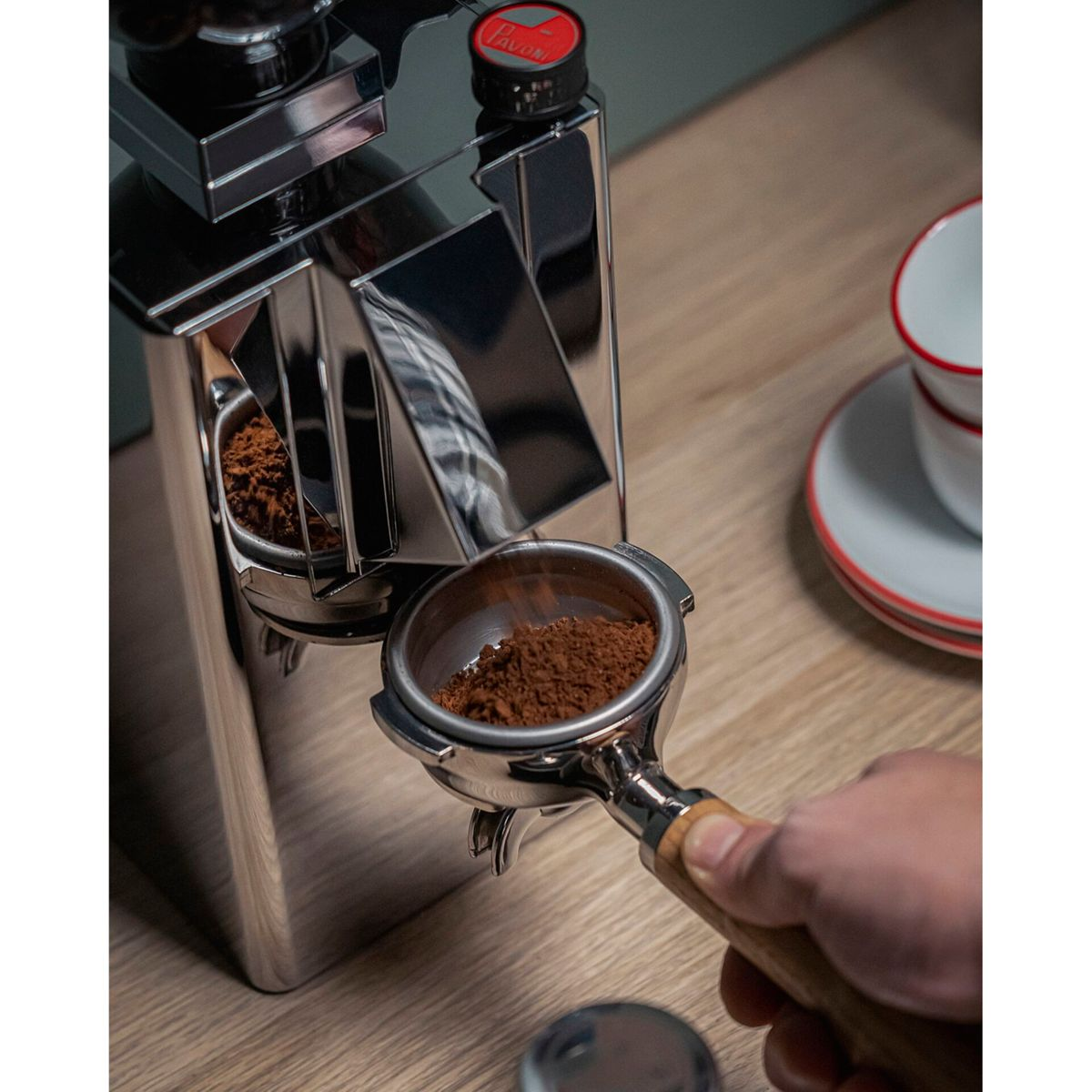 Un macinacaffè eroga caffè macinato in un portafiltro su una superficie di legno.