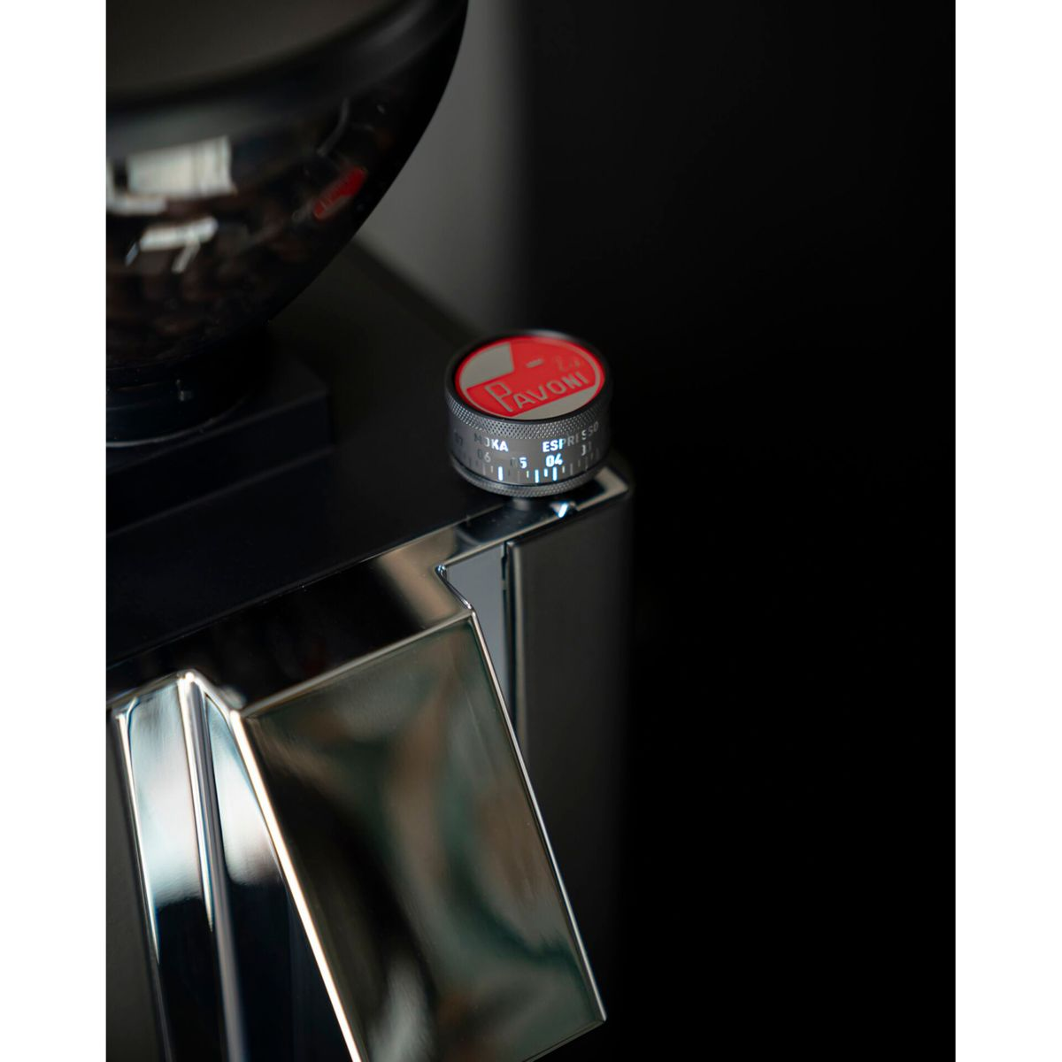Una ghiera rossa con logo Pavoni su un macinacaffè con dettagli cromati.