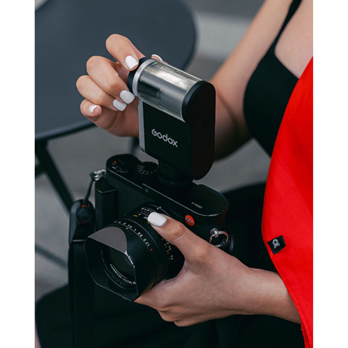 Una persona con unghie bianche tiene una fotocamera con flash.
