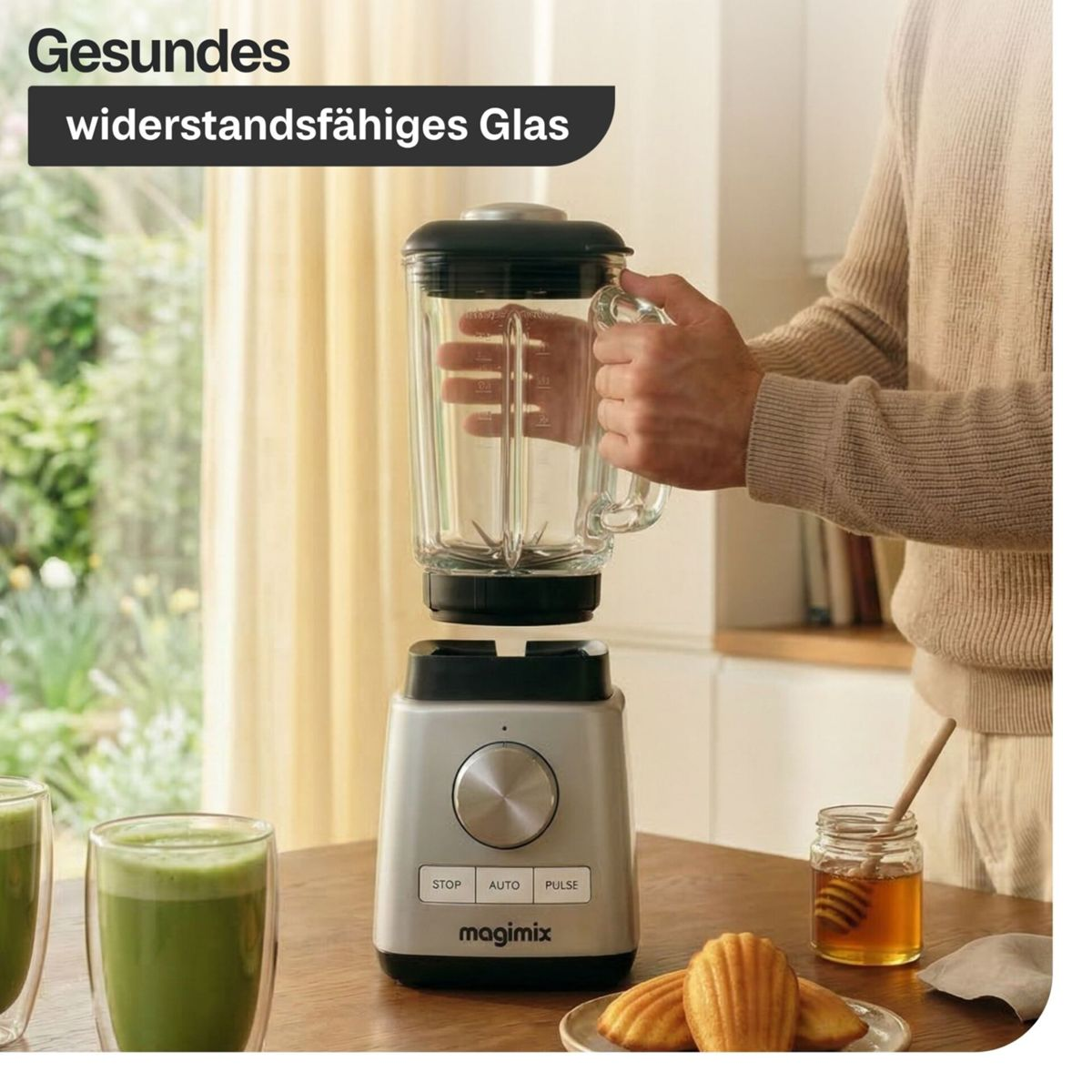 Un frullatore Magimix argentato con caraffa in vetro su tavolo di legno.