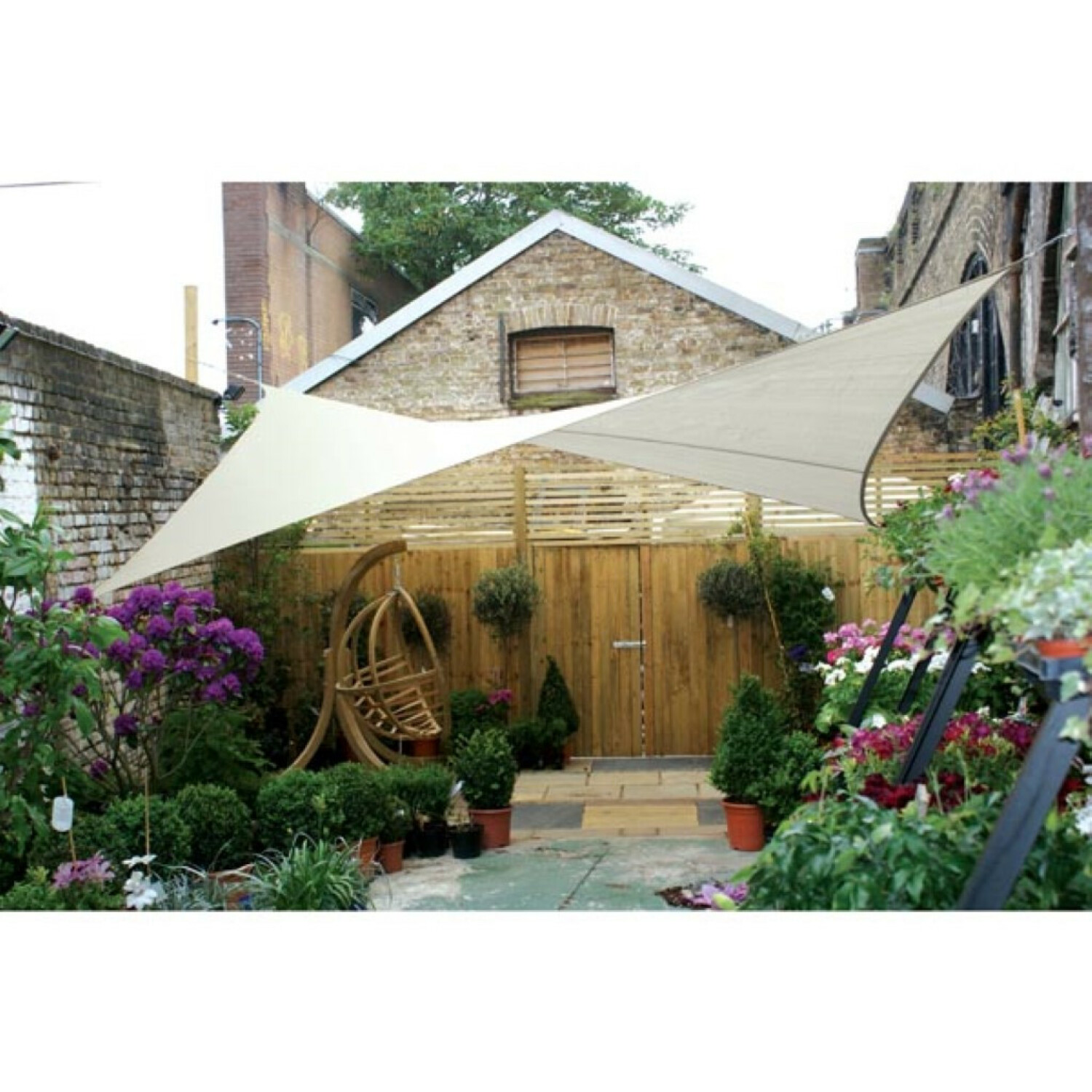 Ein Garten mit Hängesessel, Sonnensegel und üppiger Bepflanzung.