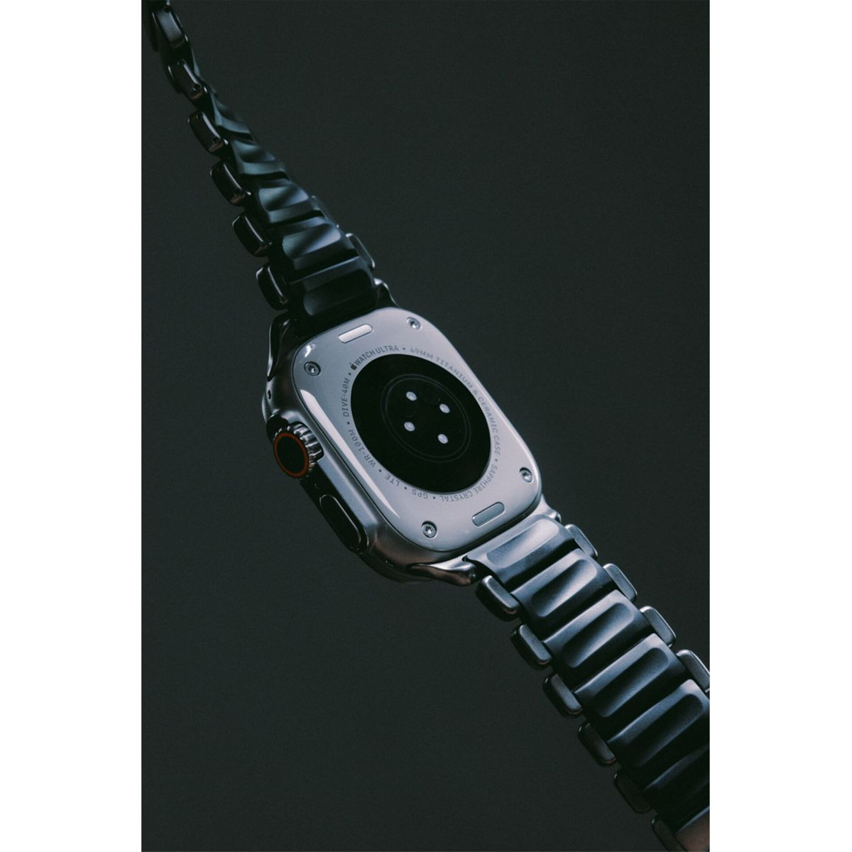 Vista posteriore di uno smartwatch argentato con cinturino in metallo nero su sfondo scuro.