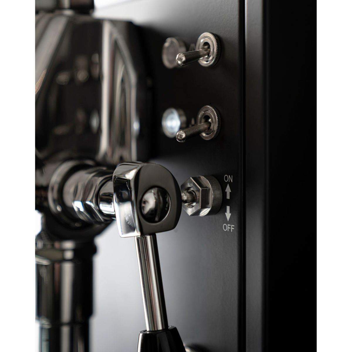 Eine Espresso-Maschine mit Chromhebel und Kippschaltern auf schwarzem Gehäuse.