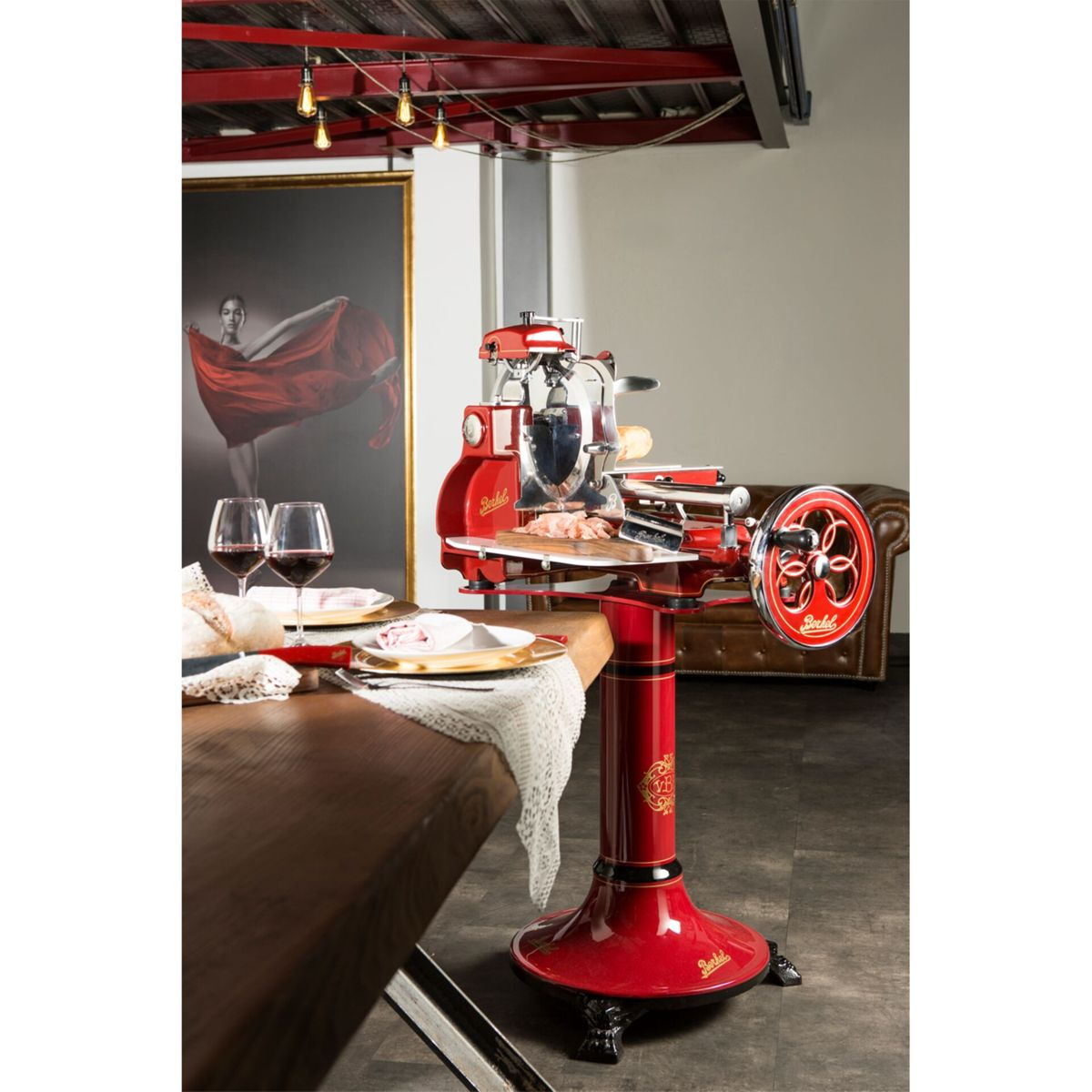 Ein roter Aufschnittschneider steht auf einem Tisch mit Fleisch und Wein.