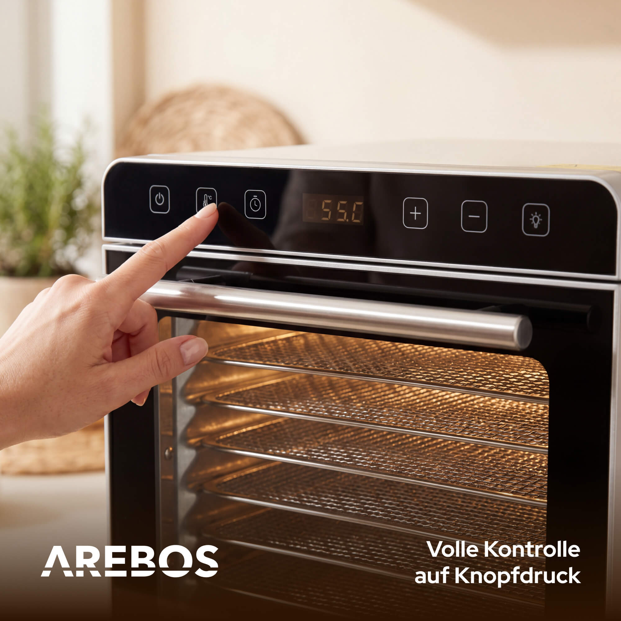 Eine Hand drückt einen Knopf auf dem Bedienfeld eines Dörrgeräts mit 55°C.