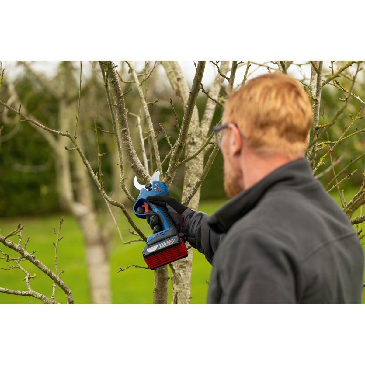 Mann mit elektrischer Astschere im Garten