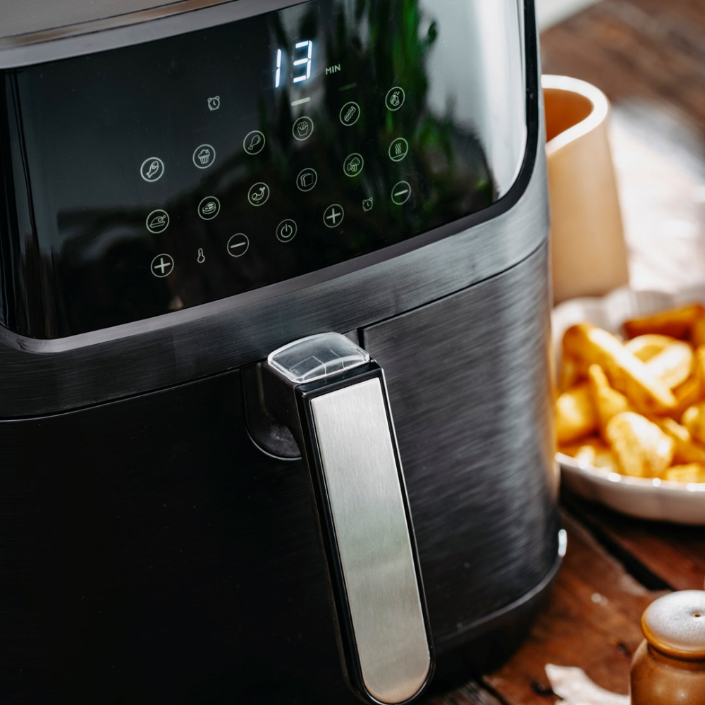 Friggitrice ad aria nera con display digitale (13 min) e icone. Patatine visibili.