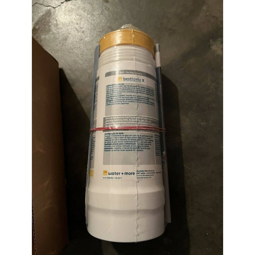 Un filtro dell'acqua bianco con tappi gialli e elastici rossi, avvolto nella plastica.