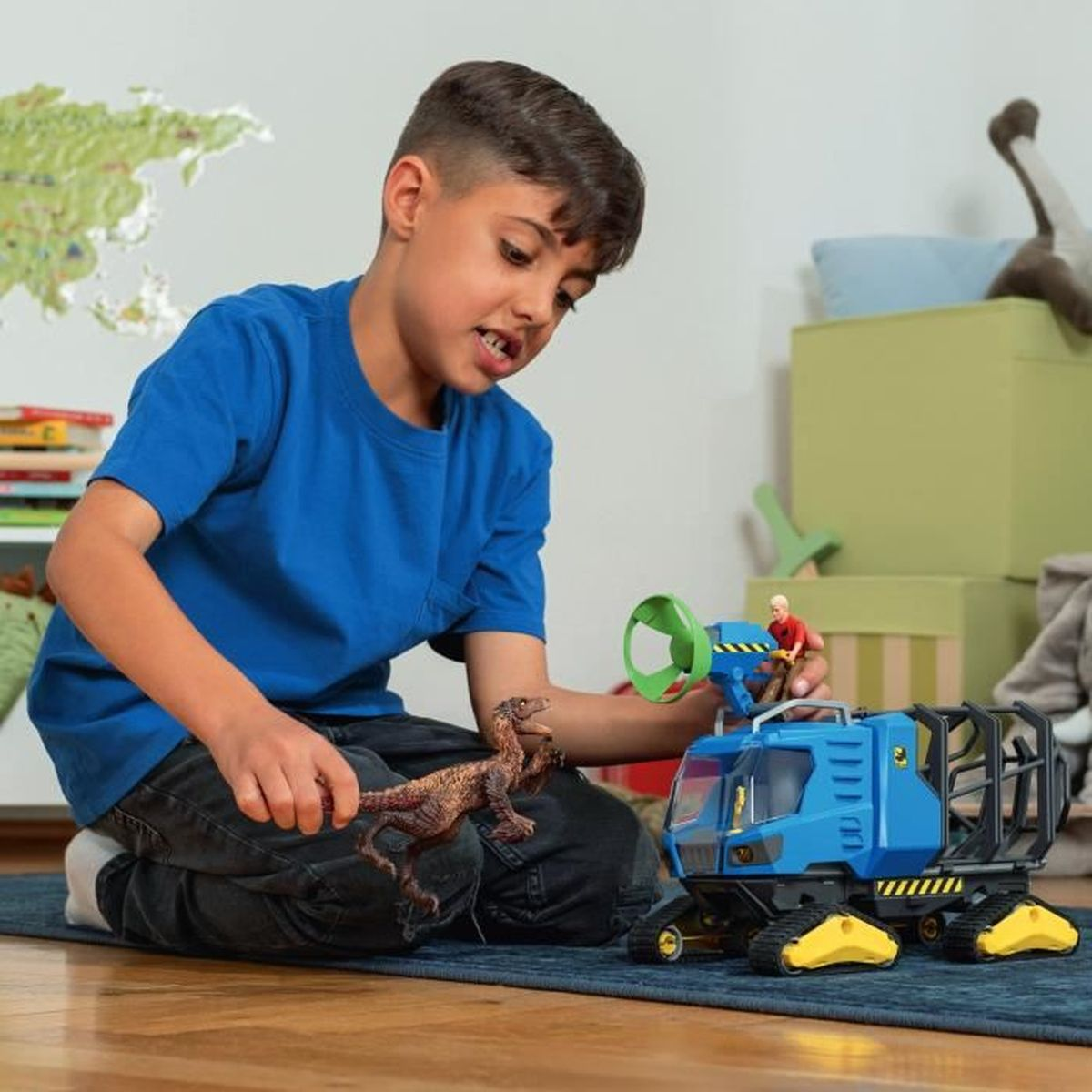 Un ragazzo gioca con un veicolo giocattolo blu e una figura di dinosauro sul pavimento.