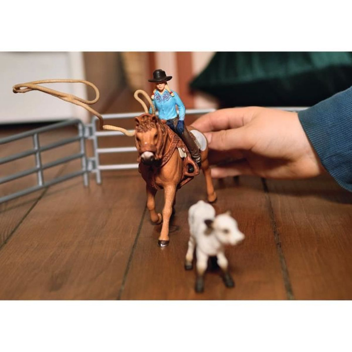 Ein Reiter auf einem braunen Pferd mit einem Lasso, neben einem Kalb.