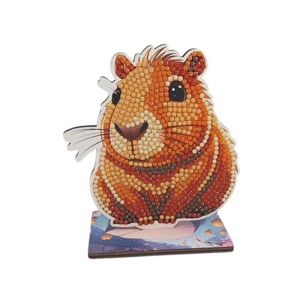 Eine funkelnde Diamantkunst-Hamsterfigur in Orange-, Braun- und Gelbtönen auf einem malerischen Sockel.