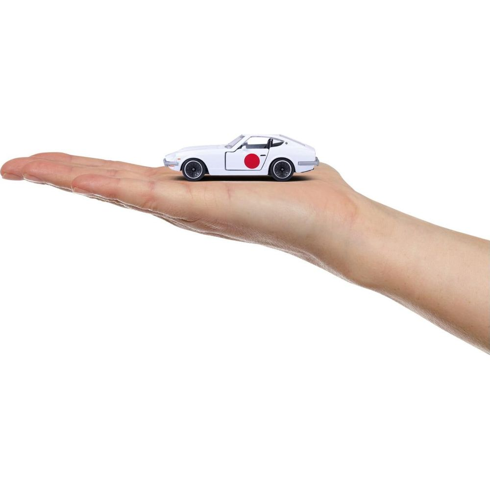 Ein weißes Spielzeugauto mit einem roten Kreis an der Seite liegt auf einer offenen Handfläche.