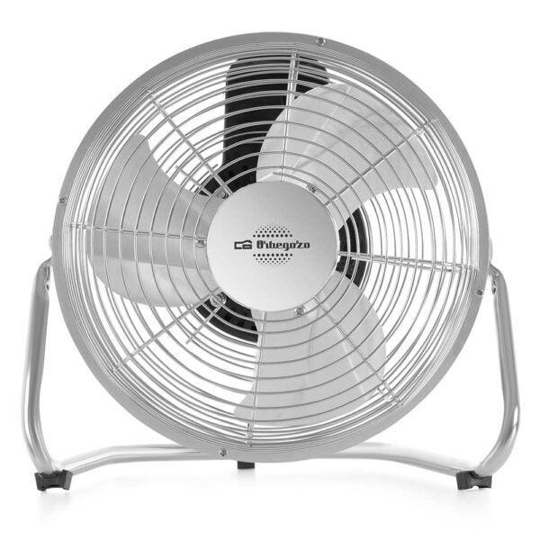 Un ventilador de pie plateado con tres aspas sobre un soporte metálico.