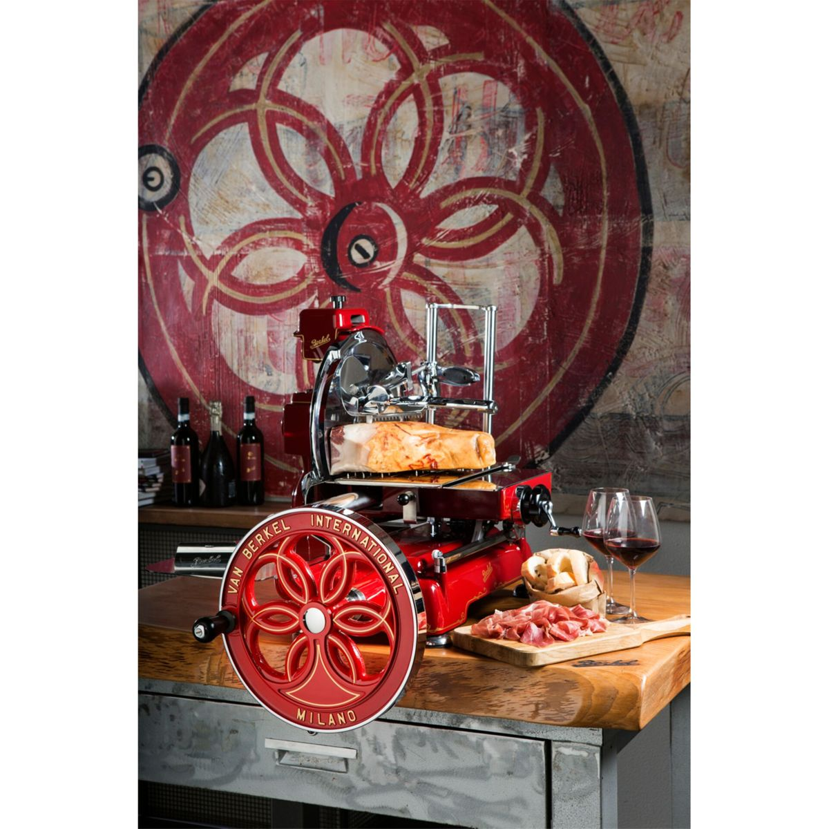 Eine rote Aufschnittmaschine mit Fleisch, Wein und Käse steht auf einem Holztisch.