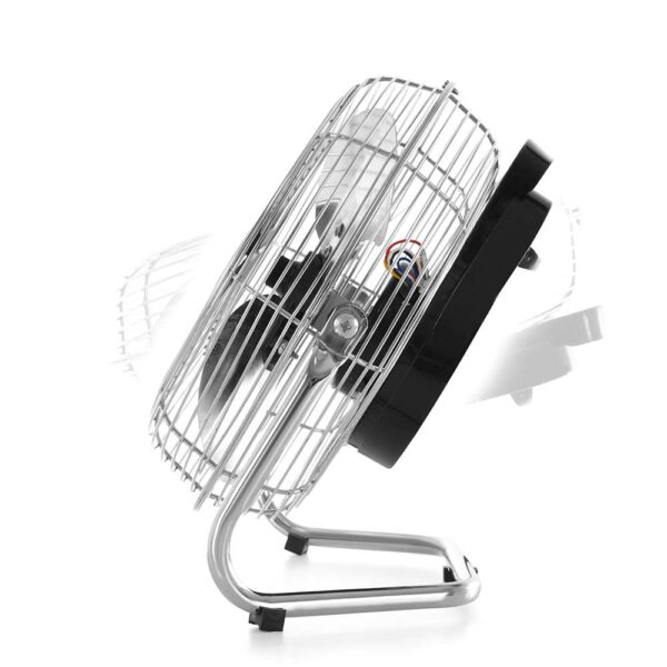 Un pequeño ventilador plateado con carcasa negra sobre base metálica. Desenfoque de movimiento.