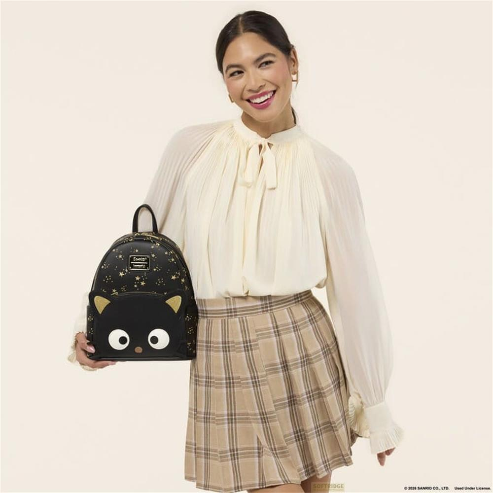 Frau mit schwarzem Rucksack mit Sternen und Katzenmotiv, cremefarbener Bluse und kariertem Rock.