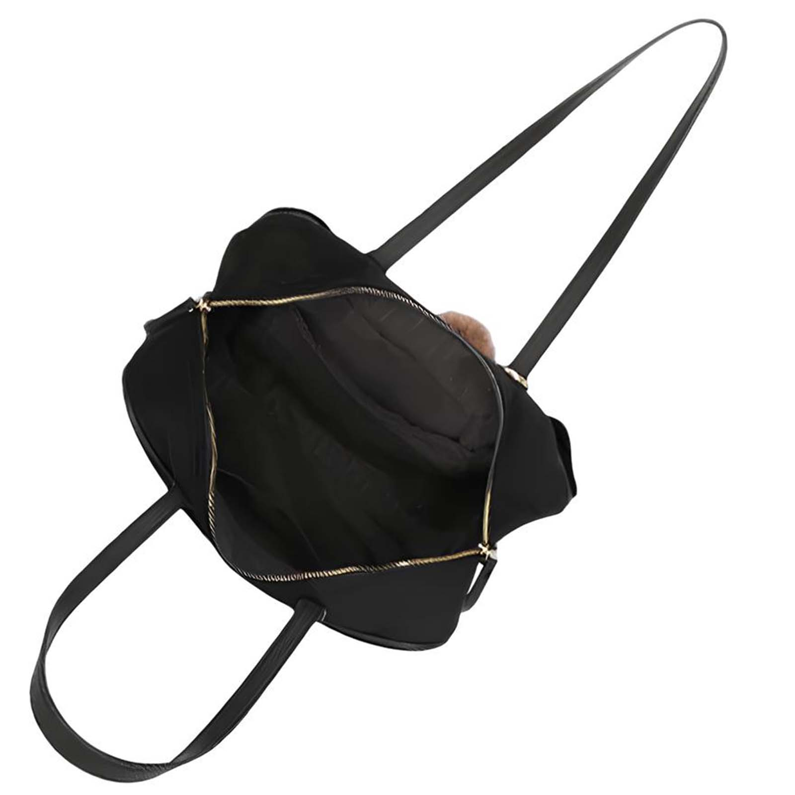 Un bolso tote negro abierto con cremallera dorada y un charm de pelo marrón.