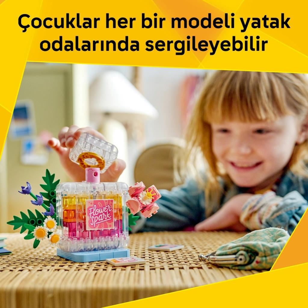 Kız, renkli tuğlalar ve çiçeklerle şeffaf bir parfüm şişesi inşa ediyor.