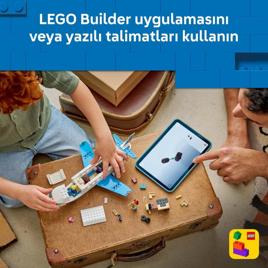 Bir çocuk, bir yetişkinin yardımıyla bir bavul üzerinde mavi LEGO uçak yapıyor.