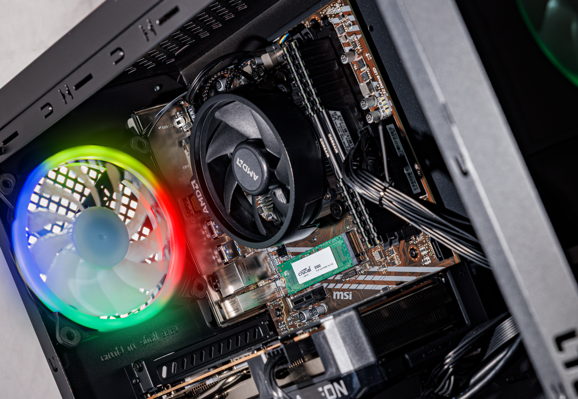 Ein PC-Gehäuse mit Hauptplatine, Lüftern und Kabeln. Ein Lüfter leuchtet bunt.