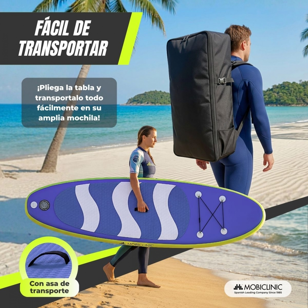 Una mujer lleva una tabla de surf inflable en la playa, un hombre con mochila pasa.
