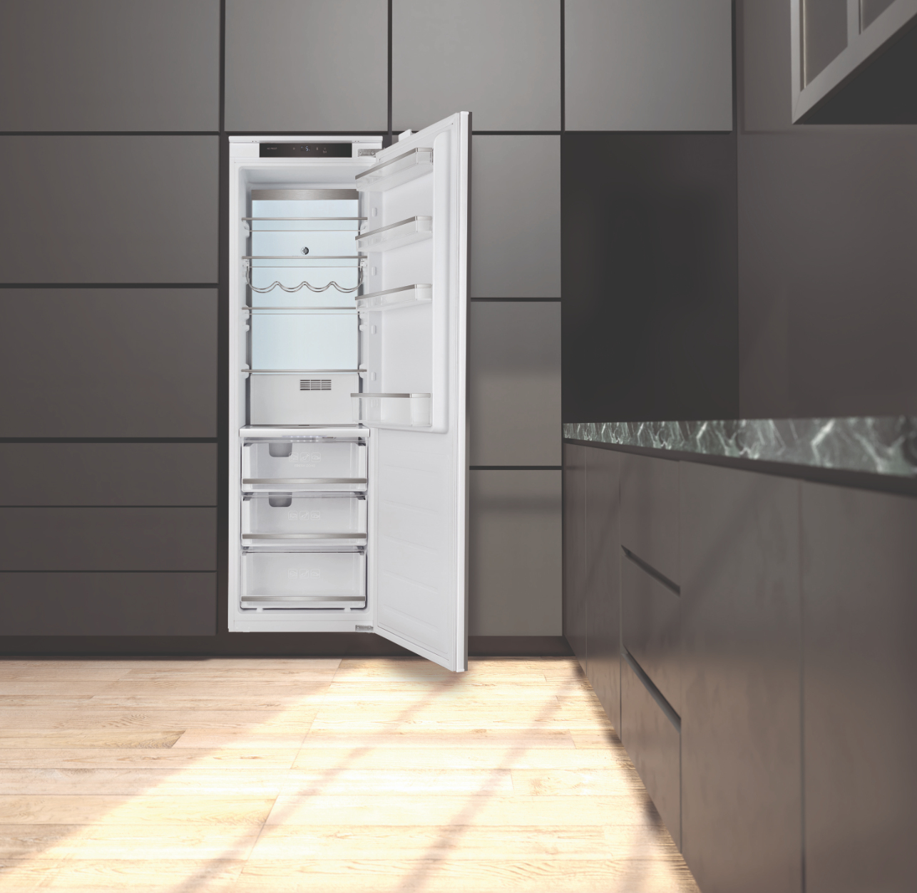 Un refrigerador blanco abierto con estantes de vidrio y cajones se alza sobre un suelo de madera.