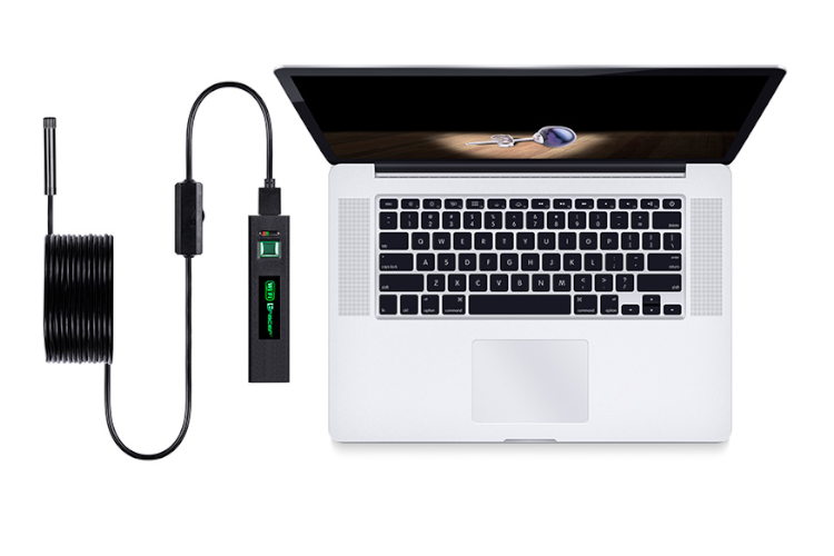 Laptop z otwartym ekranem wyświetla breloczek. Zwinięty kabel łączy się z urządzeniem.