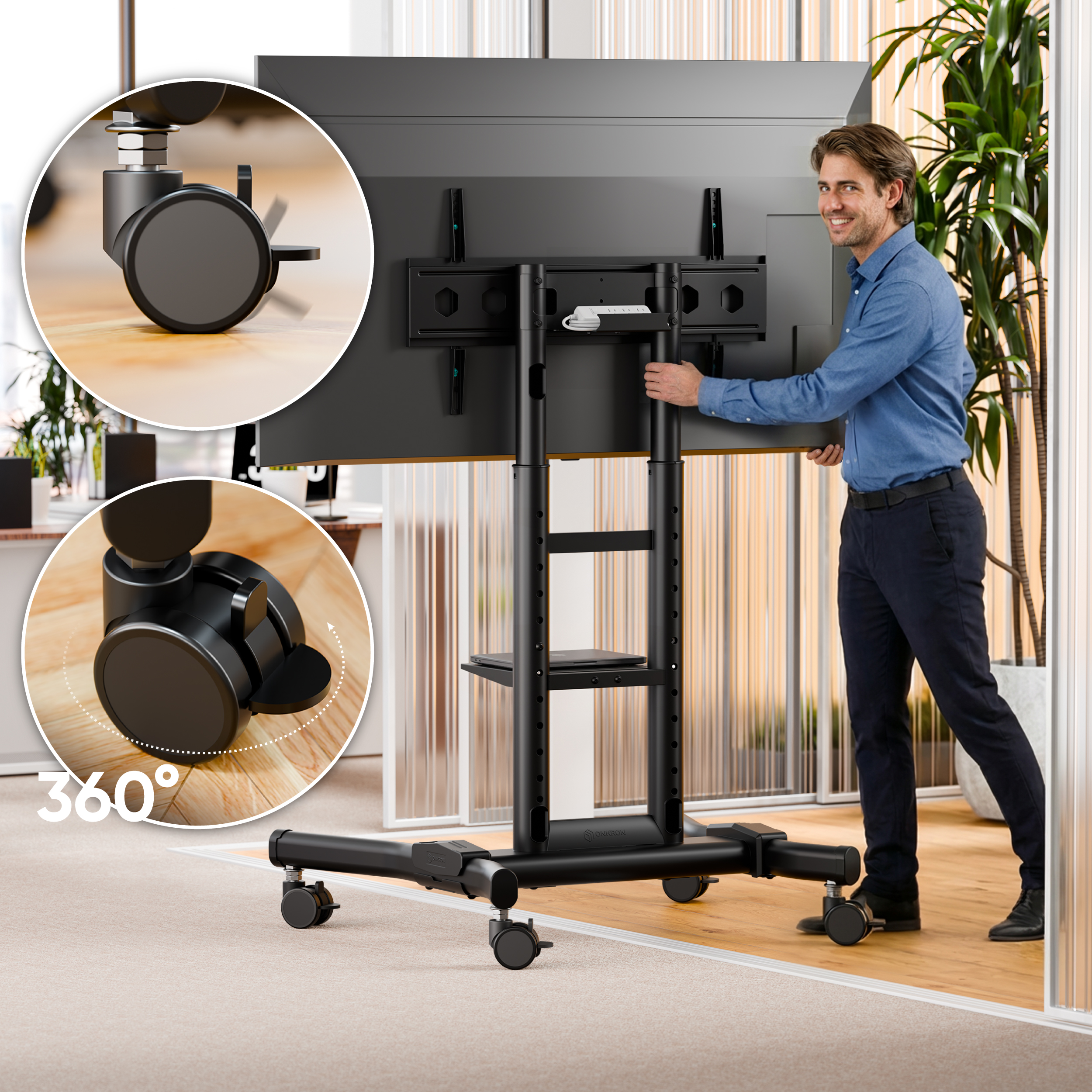Un hombre empuja un soporte de TV móvil con ruedas de 360 grados en una oficina.