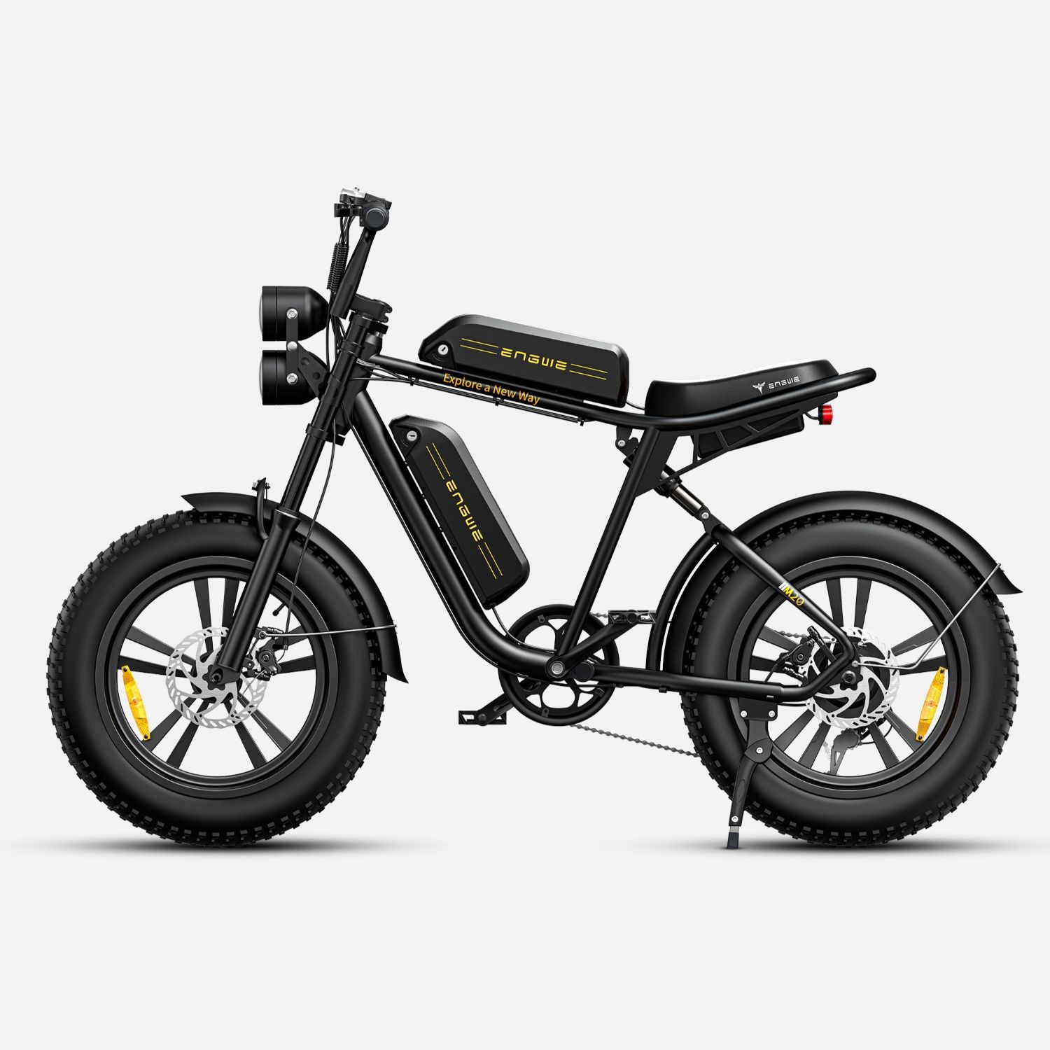 Una bicicleta eléctrica negra con neumáticos anchos, doble faro y dos baterías.