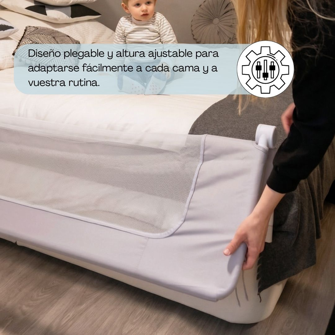 Un bebé se sienta en una cama con una barrera. Una mano ajusta la barrera.