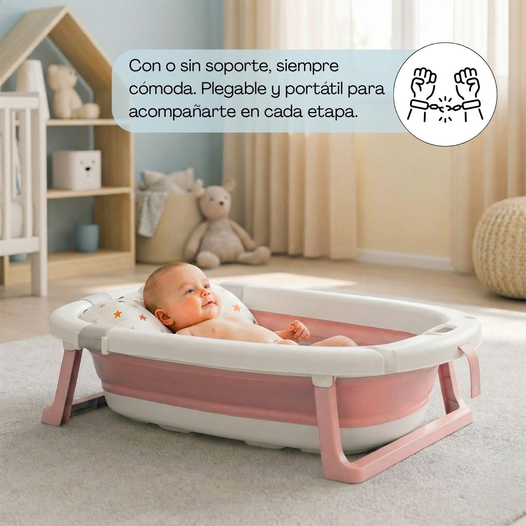 Bebé en bañera plegable rosa sobre alfombra. Fondo con estantes y juguetes.