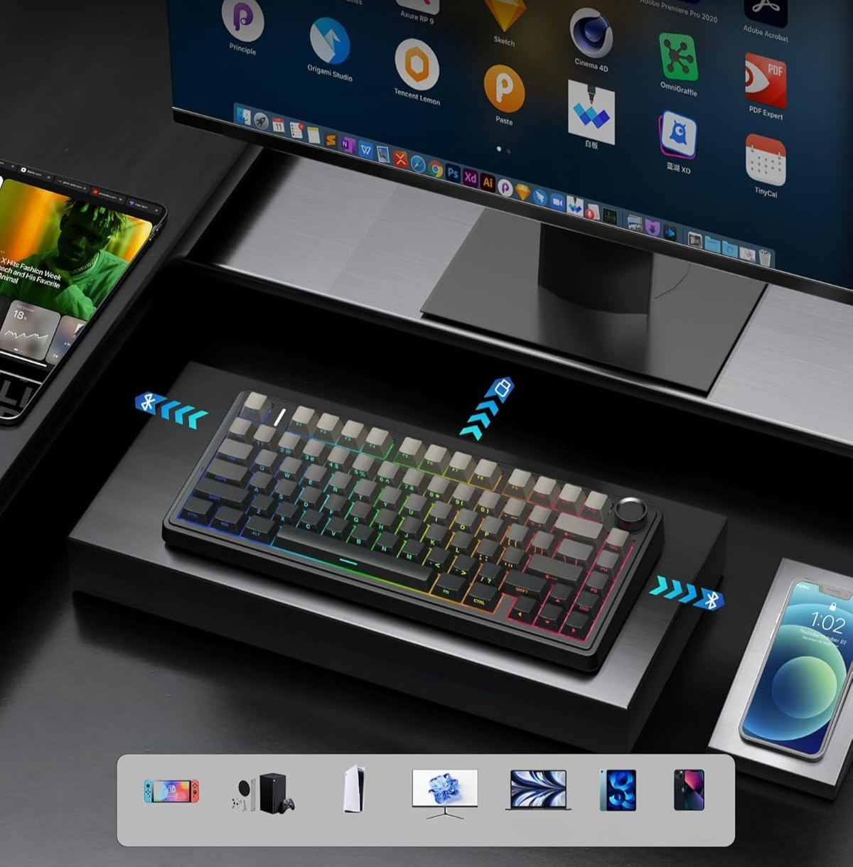 Czarna klawiatura z podświetleniem RGB, obok smartfon i ekran komputera.