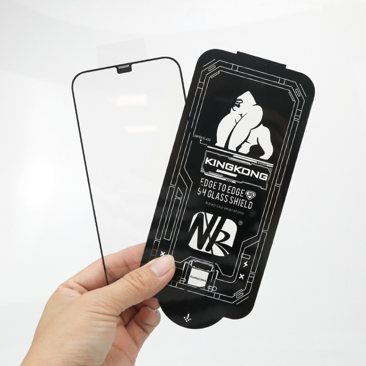 Una mano tiene una protezione per schermo con logo KingKong accanto a una protezione per schermo per smartphone.