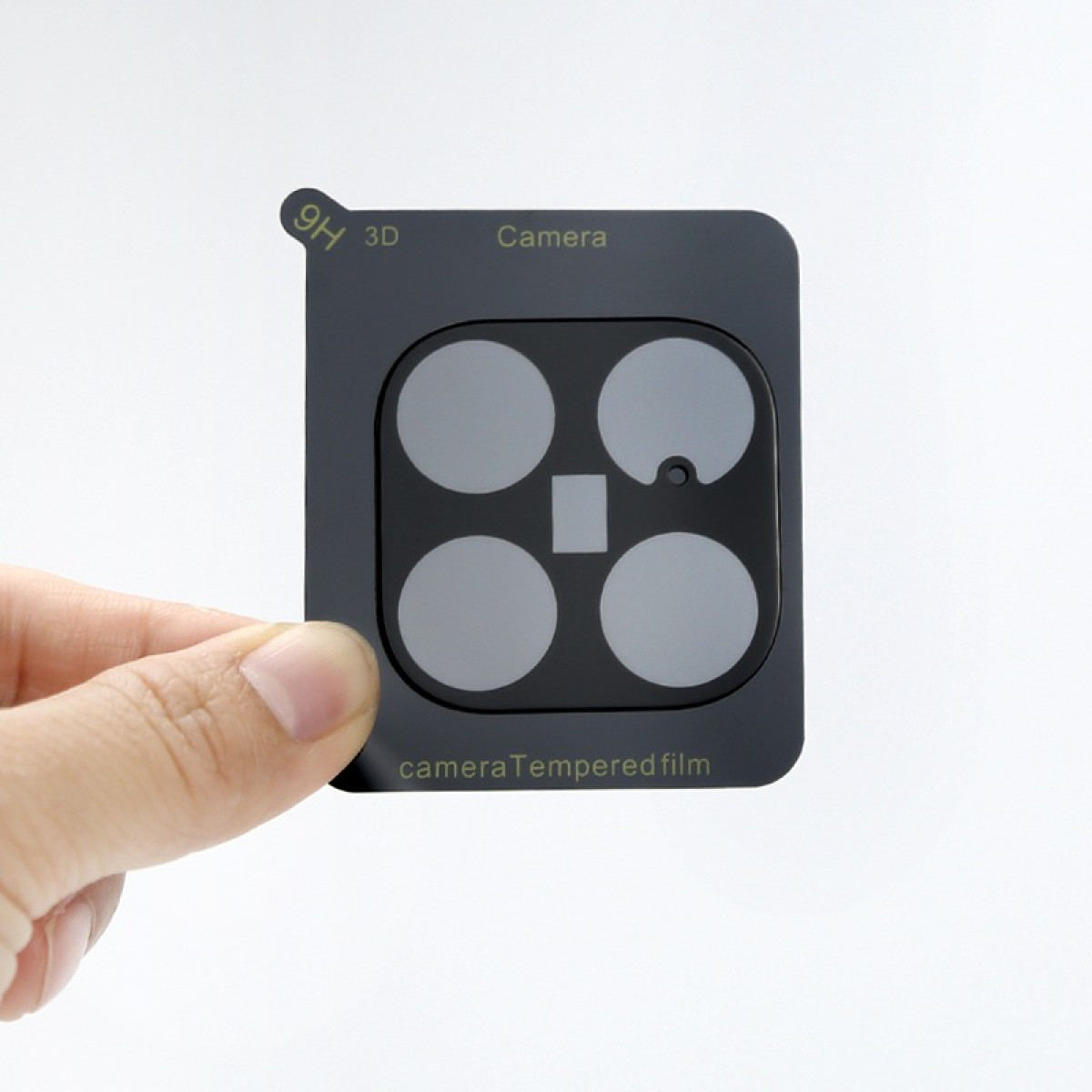Una mano tiene una protezione per obiettivo della fotocamera nera con quattro cerchi e un rettangolo.