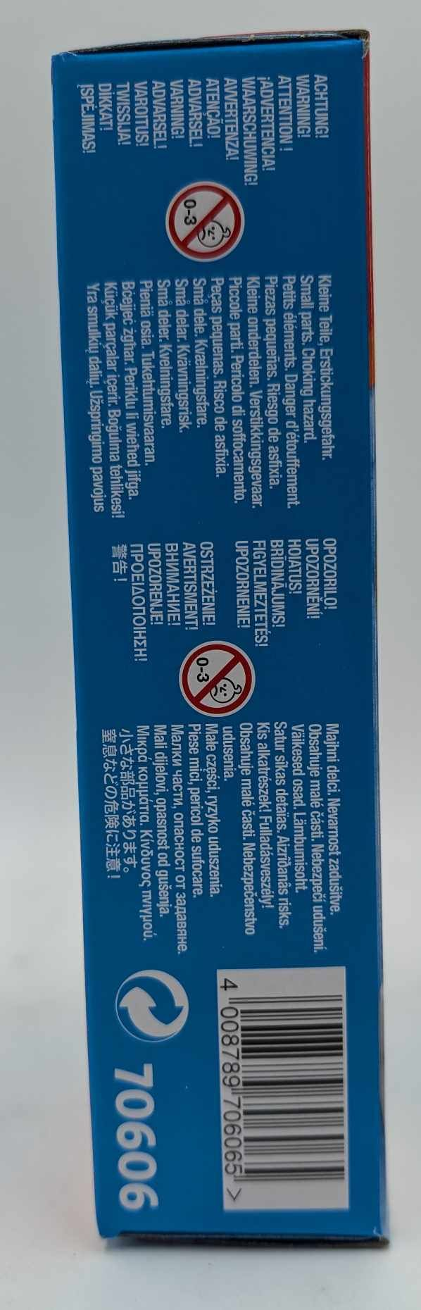 Eine blaue Box mit einem roten Kreis '0-3' Logo und mehrsprachigen Erstickungsgefahren-Warnungen, zusammen mit einem Barcode und einer Produktnummer.