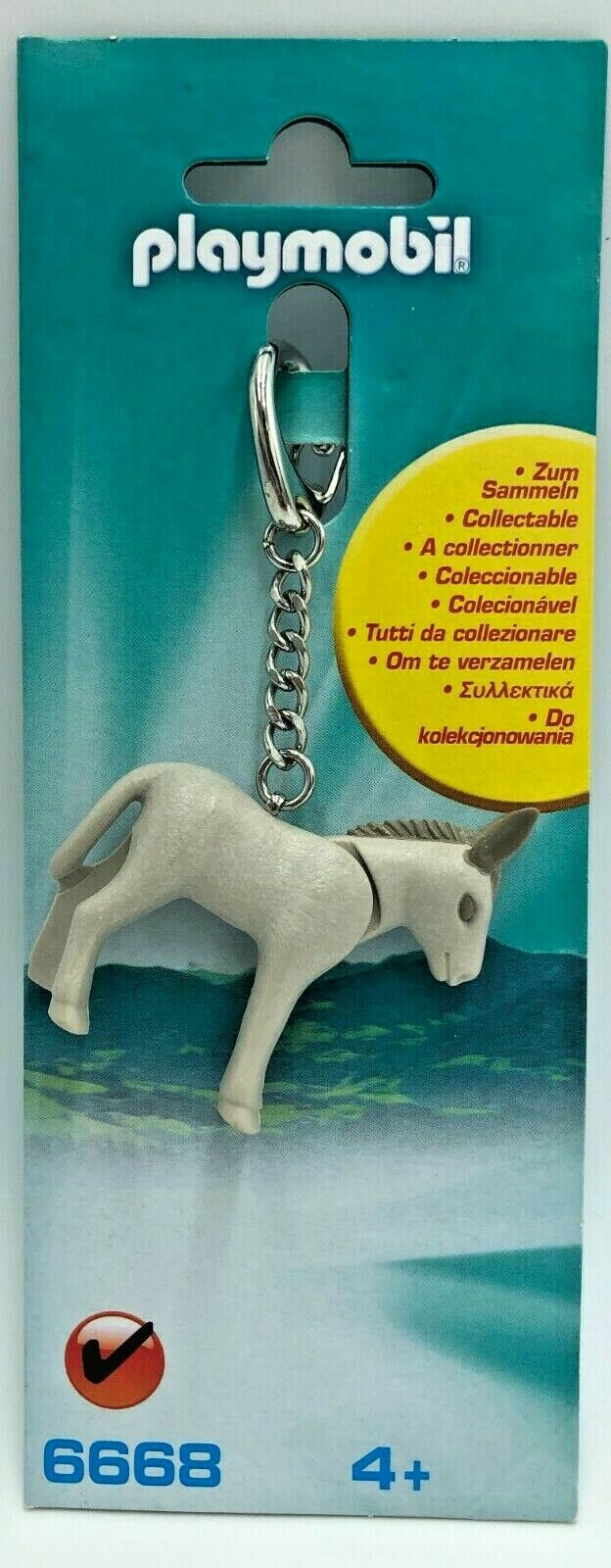 Un portachiavi Playmobil a forma di asino, grigio chiaro con criniera grigio scuro, su un imballaggio di cartone blu-verde con testo.