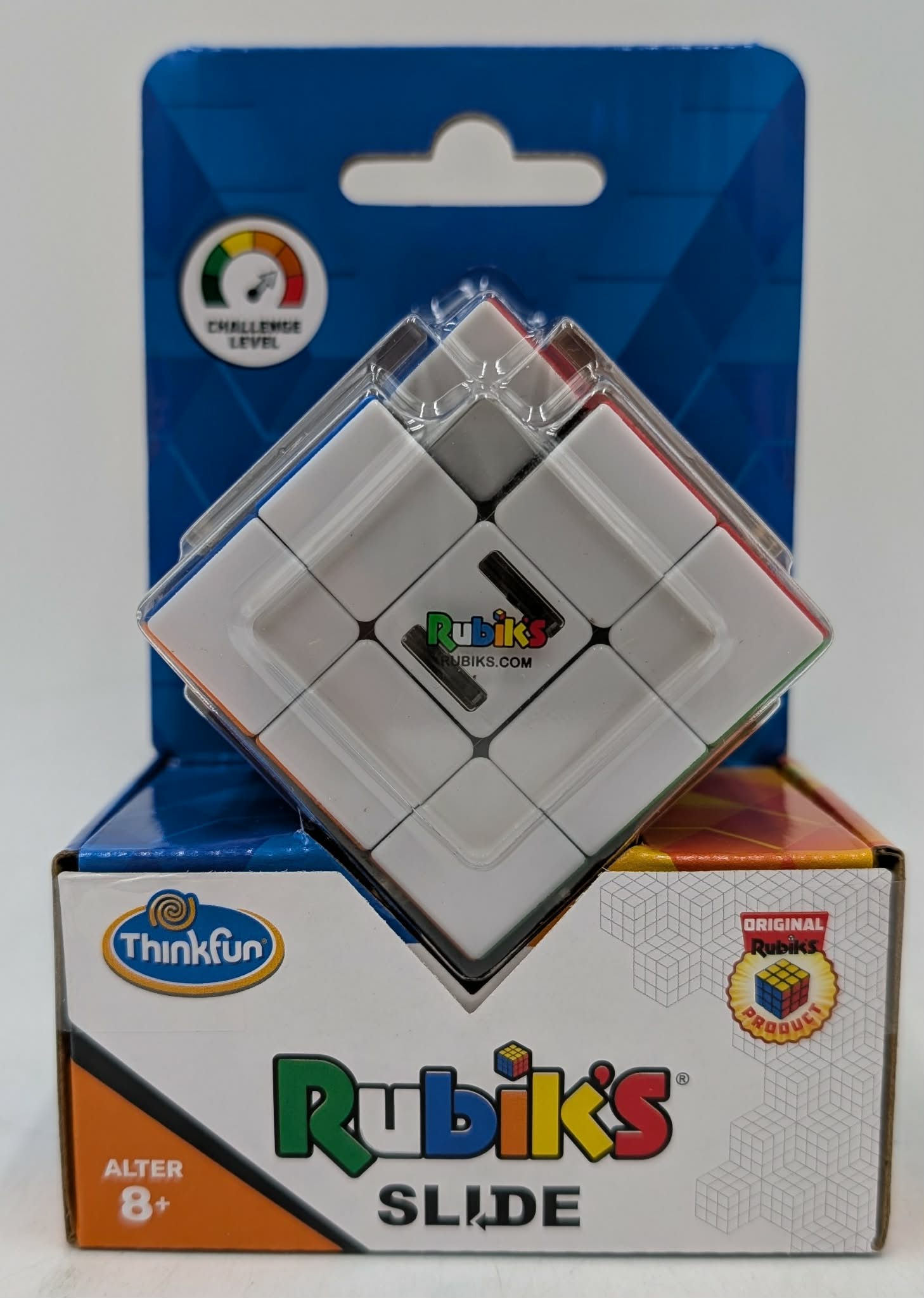 Ein Rubik's Slide Puzzle in klarer Verpackung, das weiße Quadrate mit farbigen Rändern zeigt, auf seiner farbigen Box.