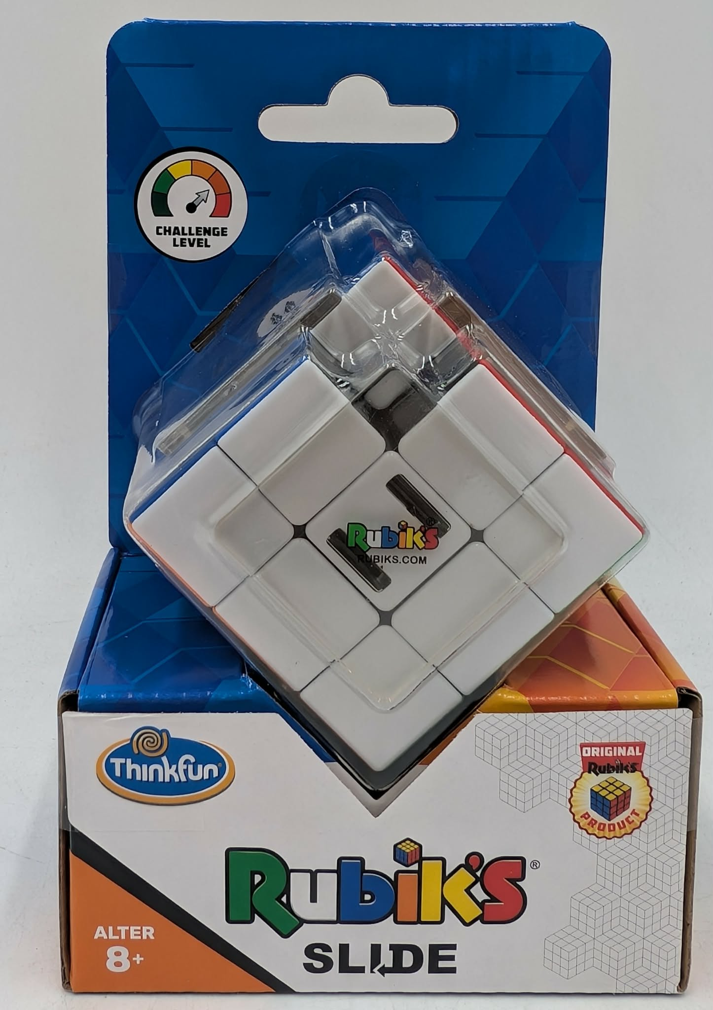 Ein Rubik's Slide Puzzle in klarer Verpackung, auf seiner orange-weißen Box, vor weißem Hintergrund.