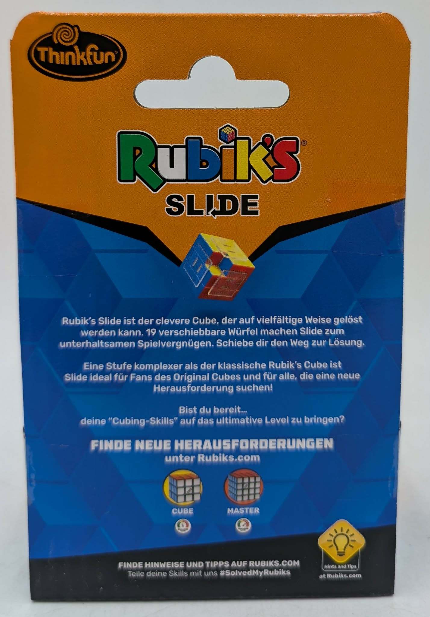 Orange-blaue Verpackung für Rubik's Slide, mit einem 3D-Rubik's Würfel, Text und Spielinformationen.