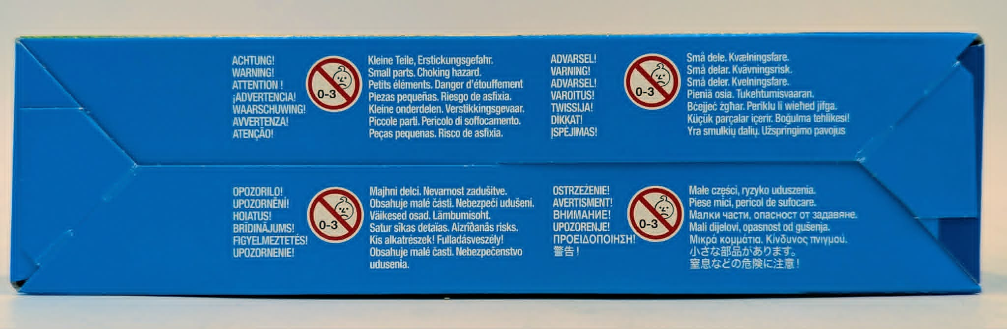 Blauer Karton mit mehrsprachigen Warnhinweisen und 0-3 Symbol.