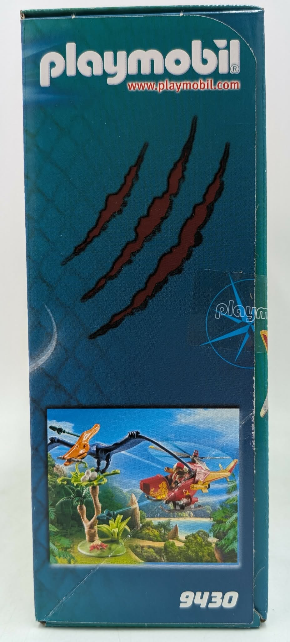 Playmobil box art with dinosaur scene, helicopter, and claw marks.