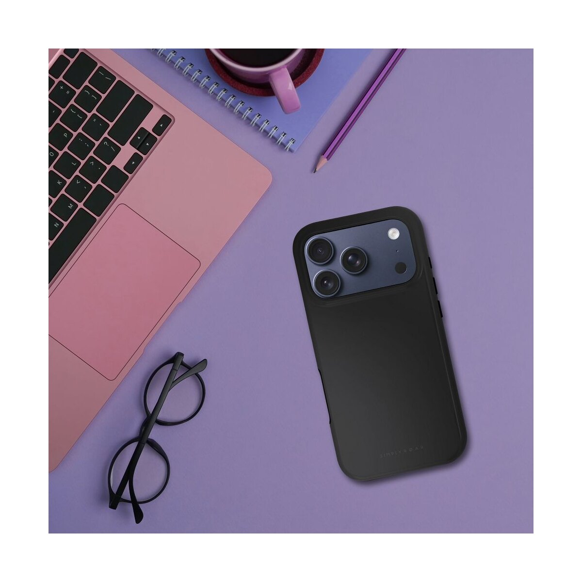 Schwarze Handyhülle, pinker Laptop, Brille, Bleistift und Kaffeetasse auf violetter Oberfläche.