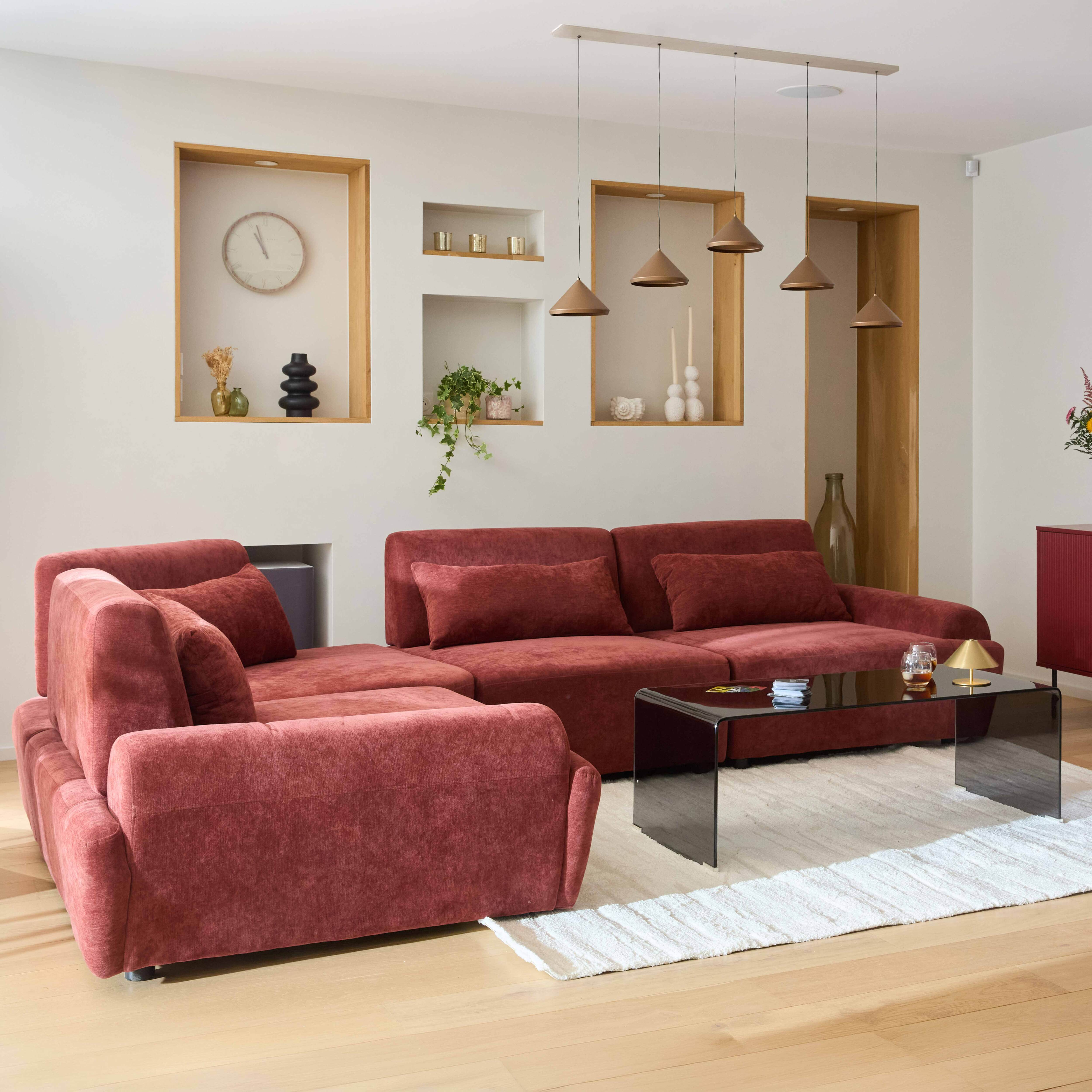 Ein rotes Ecksofa mit einem schwarzen Couchtisch und Dekorationen in Nischen.