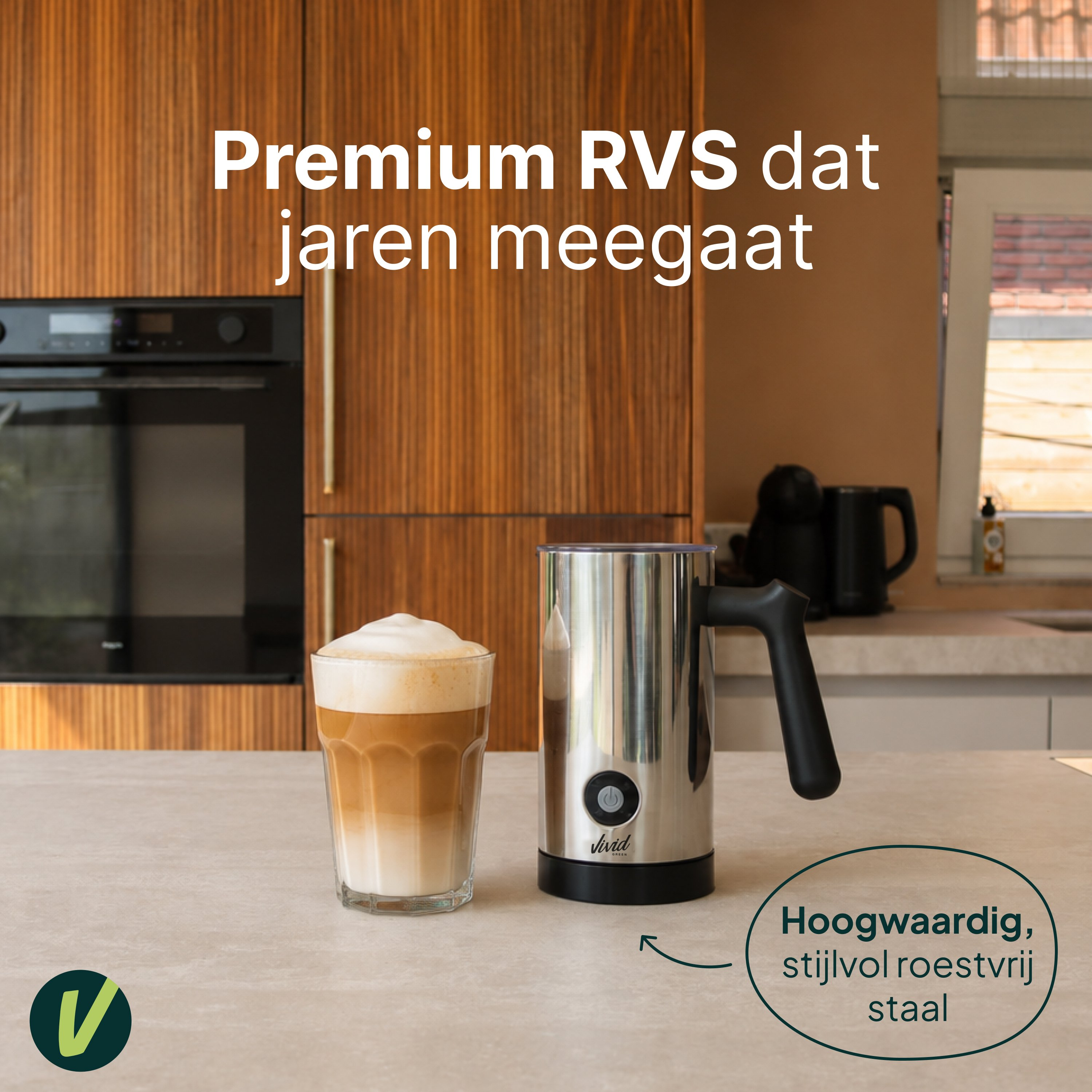 RVS melkopschuimer naast een glas latte macchiato, keuken op de achtergrond.