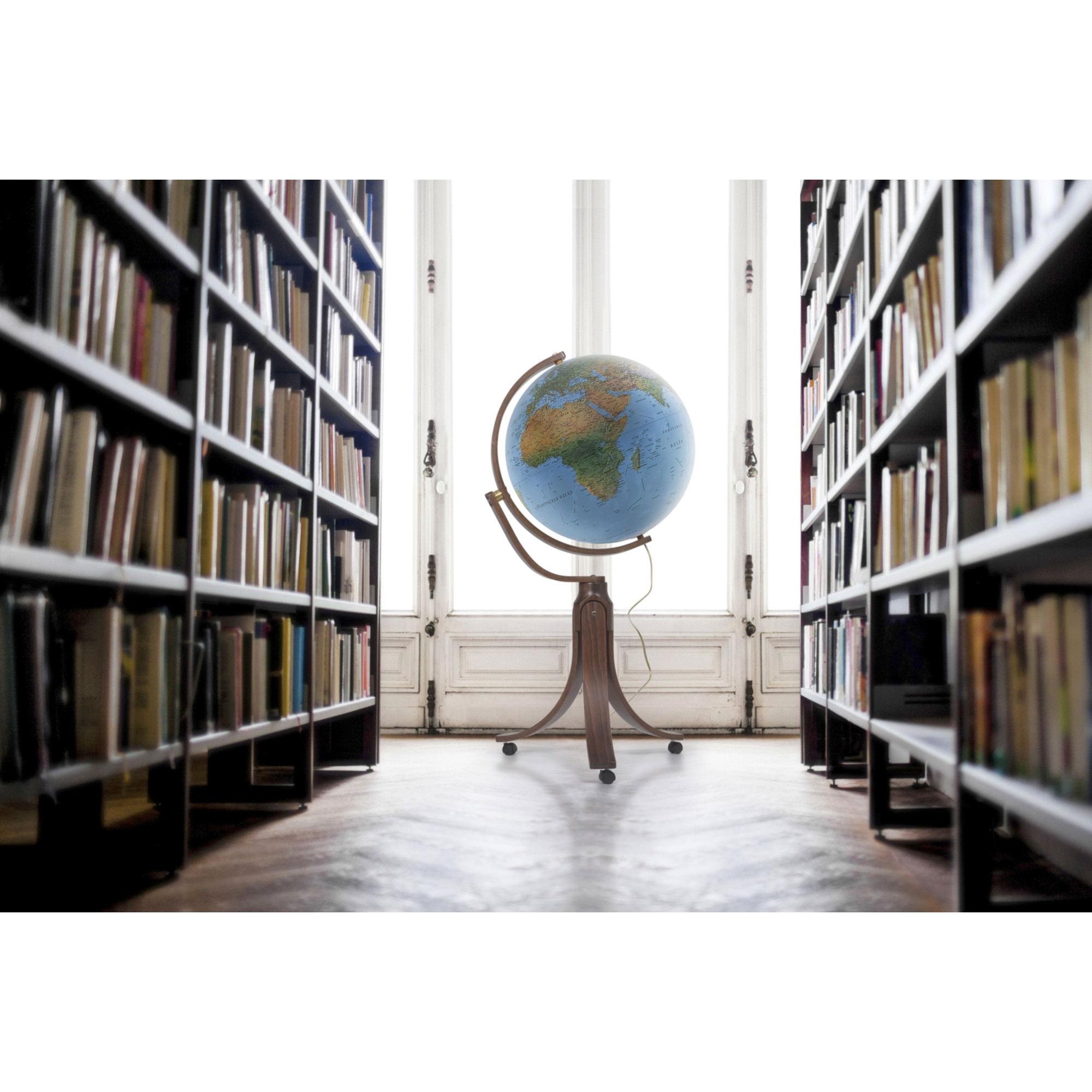 Ein Globus steht in der Mitte eines Raumes mit Bücherregalen links und rechts.