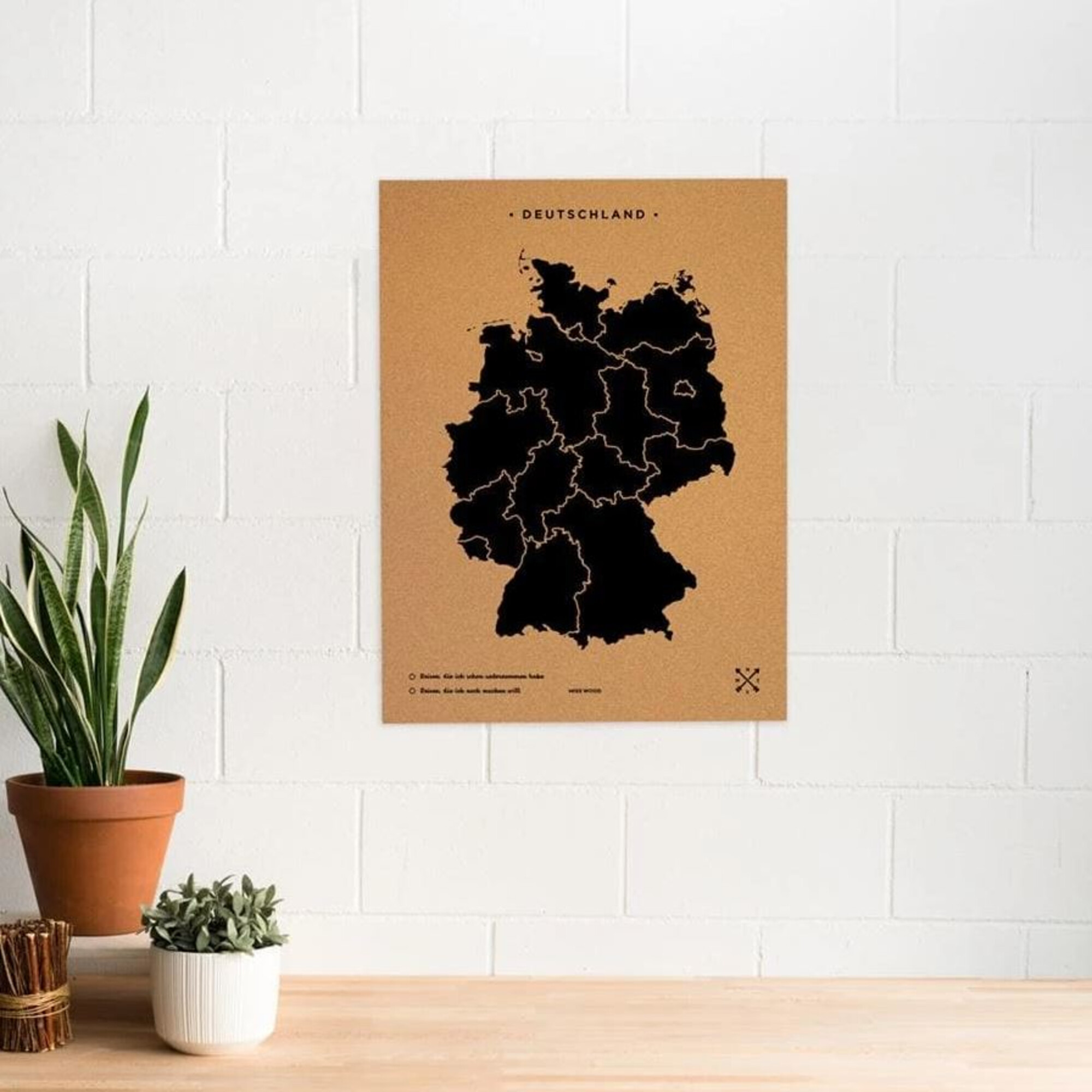 Eine schwarze Karte von Deutschland auf braunem Kork, mit Pflanzen.