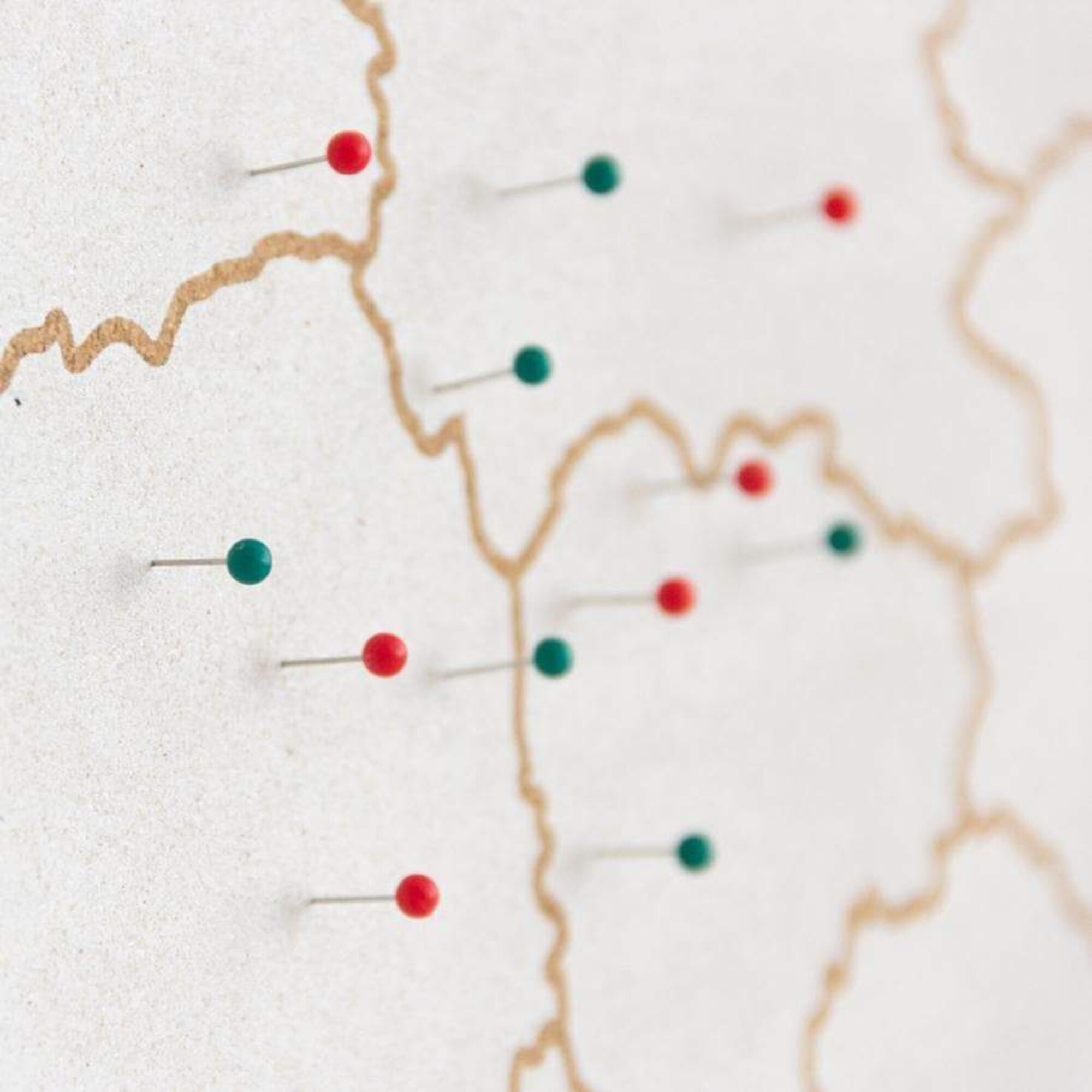 Karte mit roten und grünen Stecknadeln auf einer weißen Oberfläche.