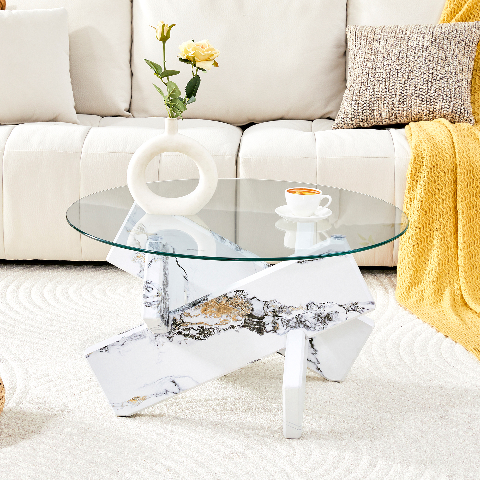 Ein Couchtisch mit Glasplatte und Marmorsockel steht auf einem cremefarbenen Teppich neben einem weißen Sofa.